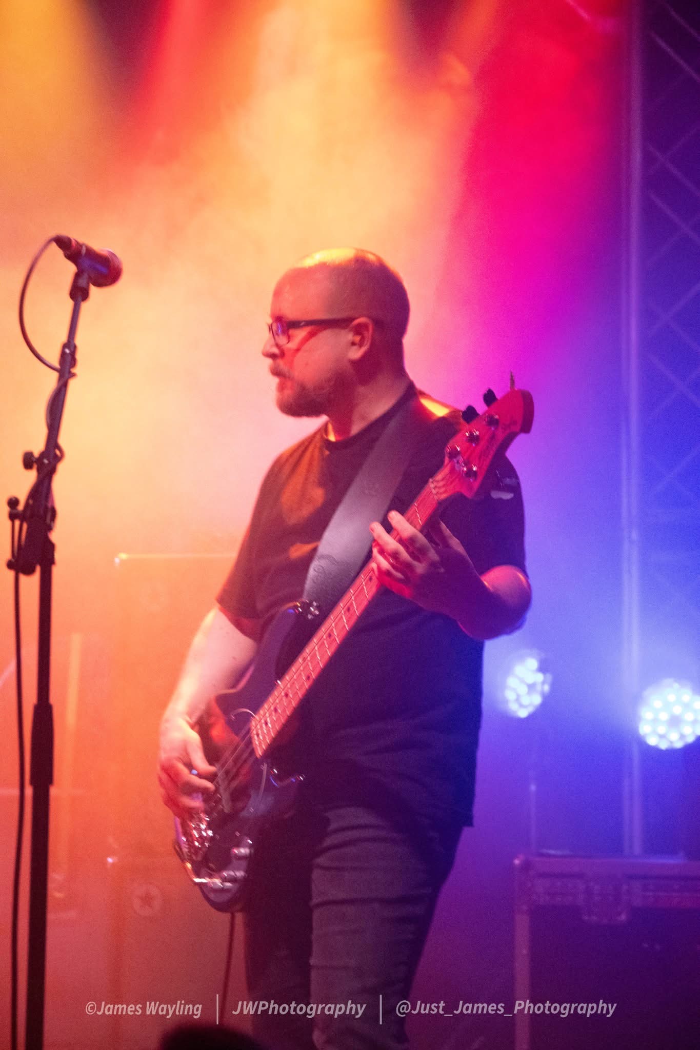 Francis bass player performing live under orange and blue stage lighting