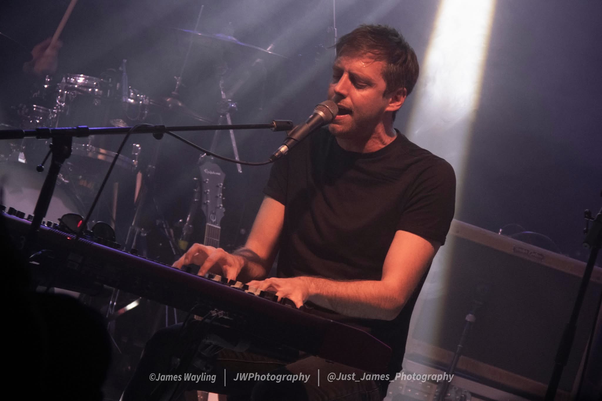 Francis keys player singing on stage, atmospheric lighting